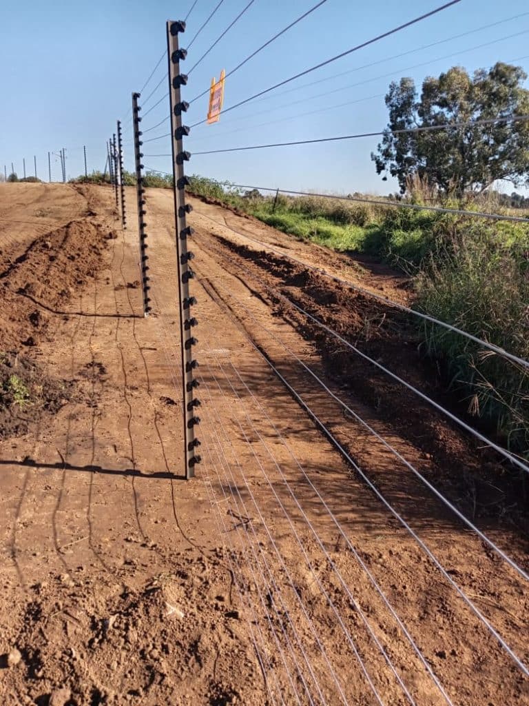 Electric fence strands and energiser on a property boundary