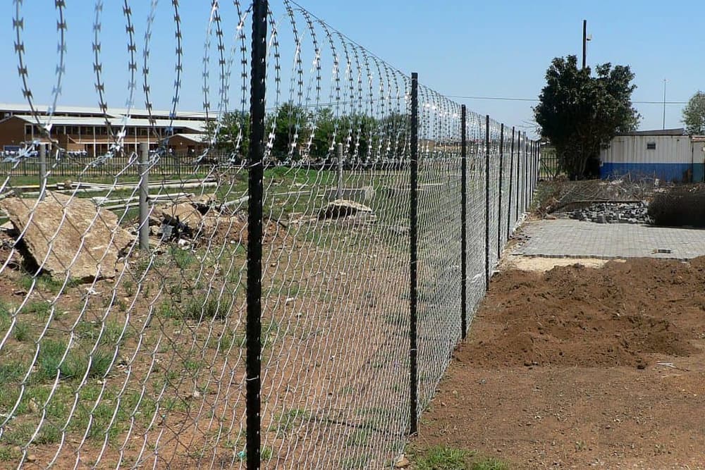 Diamond mesh fence topped with flat-wrap razor wire